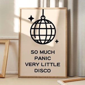 May include: A beige framed print with a black disco ball graphic and the text "So much panic very little disco".