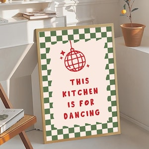 May include: A framed art print with a gold border. The print features a red disco ball illustration and the text "THIS KITCHEN IS FOR DANCING" in red. The border is a green and white checkerboard pattern.