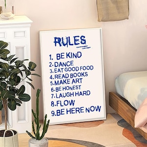 Könnte beinhalten: Weißer gerahmter Poster mit dem Wort "RULES" in blauer Schrift. Der Poster listet neun Regeln in blauer Schrift auf, darunter "Be Kind", "Dance", "Eat Good Food", "Read Books", "Make Art", "Be Honest", "Laugh Hard", "Flow" und "Be Here Now".