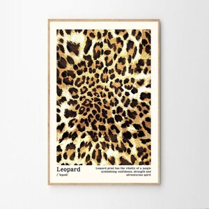 May include: A framed print featuring a leopard print pattern in shades of brown and tan. The print includes the word "Leopard" and text describing the print's symbolism. The artwork is displayed in a light-colored wooden frame.