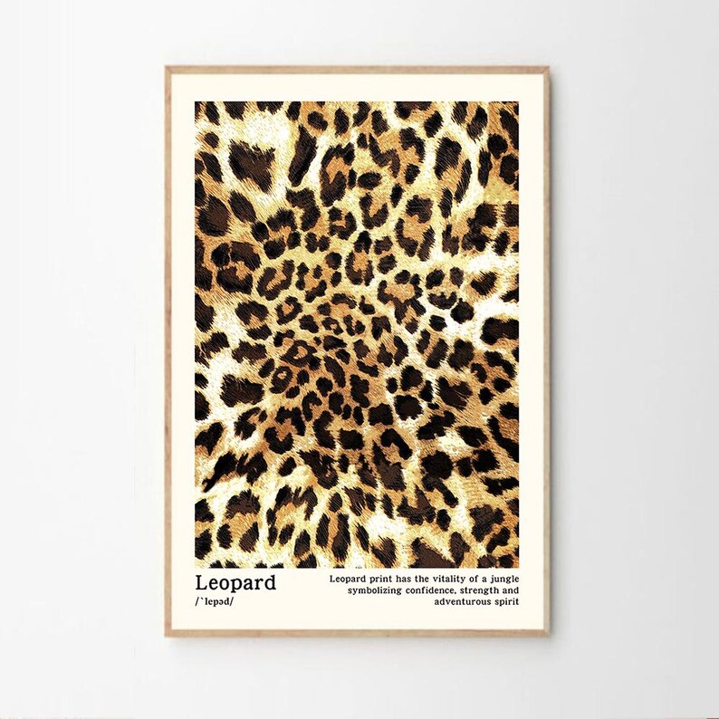May include: A framed print featuring a leopard print pattern in shades of brown and tan. The print includes the word "Leopard" and text describing the print's symbolism. The artwork is displayed in a light-colored wooden frame.