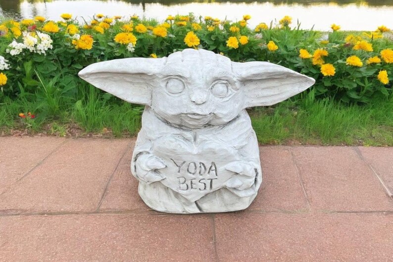 Pu&ograve; includere: Una statua di cemento grigio di un personaggio del franchise di Star Wars, che tiene un cartello a forma di cuore che dice "Yoda Best".