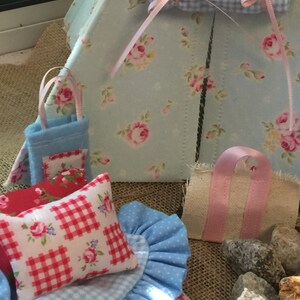 May include: A miniature blue and white gingham tent with a pink and white floral print. The tent has a small blue pillow with a red and white gingham print and a pink and white floral print. There is a small blue and white gingham blanket and a small pink and white floral print bag.
