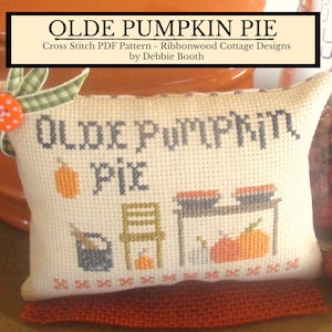 May include: A cross stitch pattern for a pillow featuring the text "Olde Pumpkin Pie" with a pumpkin, pie, and a chair. The pattern is by Ribbonwood Cottage Designs by Debbie Booth.