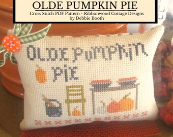 May include: A cross stitch pattern for a pillow featuring the text "Olde Pumpkin Pie" with a pumpkin, pie, and a chair. The pattern is by Ribbonwood Cottage Designs by Debbie Booth.