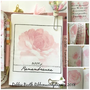 May include: A pink watercolor rose with the words "BOOK of Remembrance" written in black ink. The text "Debbie Booth Ribbonwoodplanner 2018" is written at the bottom of the page.