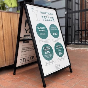 Può includere: Un cartello nero a forma di A con testo bianco che pubblicizza un ristorante chiamato "TELLER". Il cartello elenca le specialità giornaliere, tra cui Roast della domenica a $25, Schnitzel del lunedì a $20, Steak Night a $25 e Trivia del giovedì. Il cartello include anche l'indirizzo del sito web del ristorante: tir.au/nye.