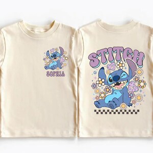 two white t-shirts with a cartoon character design and text printed on them.