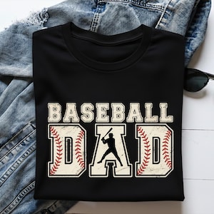 Op de afbeelding: Zwart T-shirt met de tekst "BASEBALL DAD" in een distressed, vintage stijl. De letter "D" is ontworpen als een honkbal met rode stiksels. Een silhouet van een honkbalspeler staat in het midden.