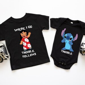 The image displays two black t-shirts with cartoon characters and text printed on them, along with a pair of black and white sneakers.