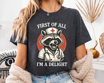 First Of All I'm A Delight Nurse Shirt, Raccoon Nurse Sweatshirt, Sarcastic Raccon Nursing School Hoodie, Funny Nurse Gift Tee