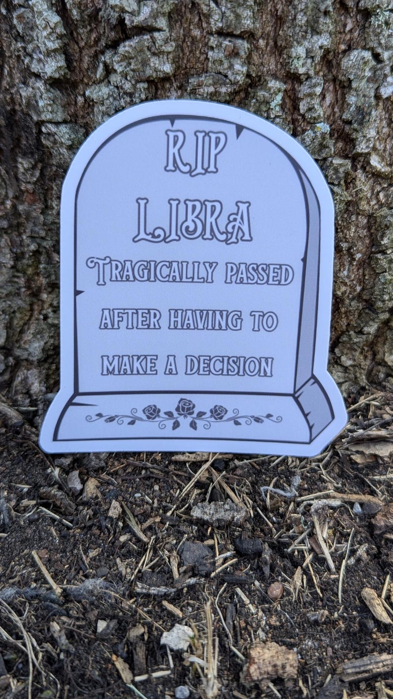May include: A white tombstone with the text "RIP LIBRA TRAGICALLY PASSED AFTER HAVING TO MAKE A DECISION" and a floral design at the bottom.