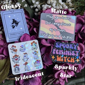 May include: A set of four stickers featuring different designs. The first sticker is glossy and features a black silhouette of a witch riding a broom with a black cat. The text "Childless Cat Lady" is printed below the image. The second sticker is matte and features a rainbow background with the text "May you have the confidence of a man sending a d*ck pic." The third sticker is iridescent and features a repeating pattern of ghosts wearing cowboy hats and holding guns. The fourth sticker is sparkly and features the text "Spooky Feminist Witch" in a rainbow font with glitter accents.