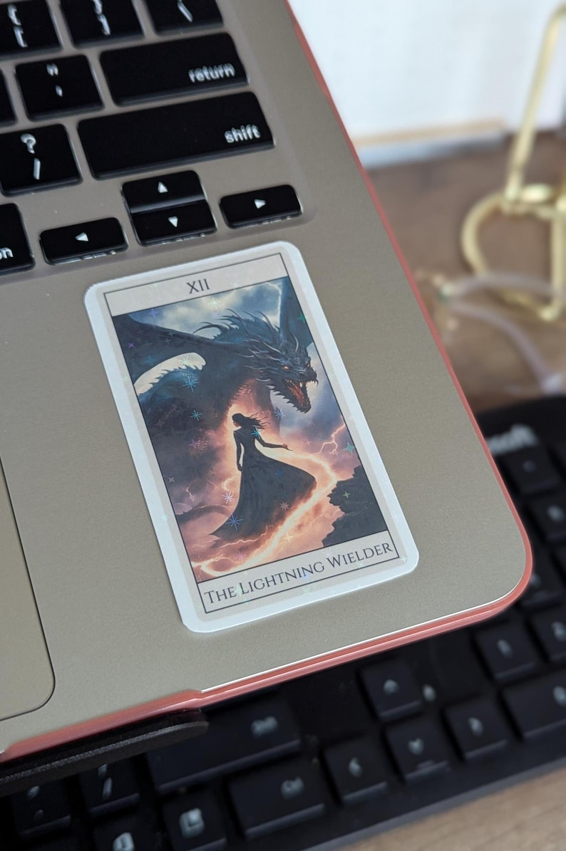 May include: A tarot card featuring a black dragon and a woman in a long dress. The card is labelled "XII THE LIGHTNING WIELDER".