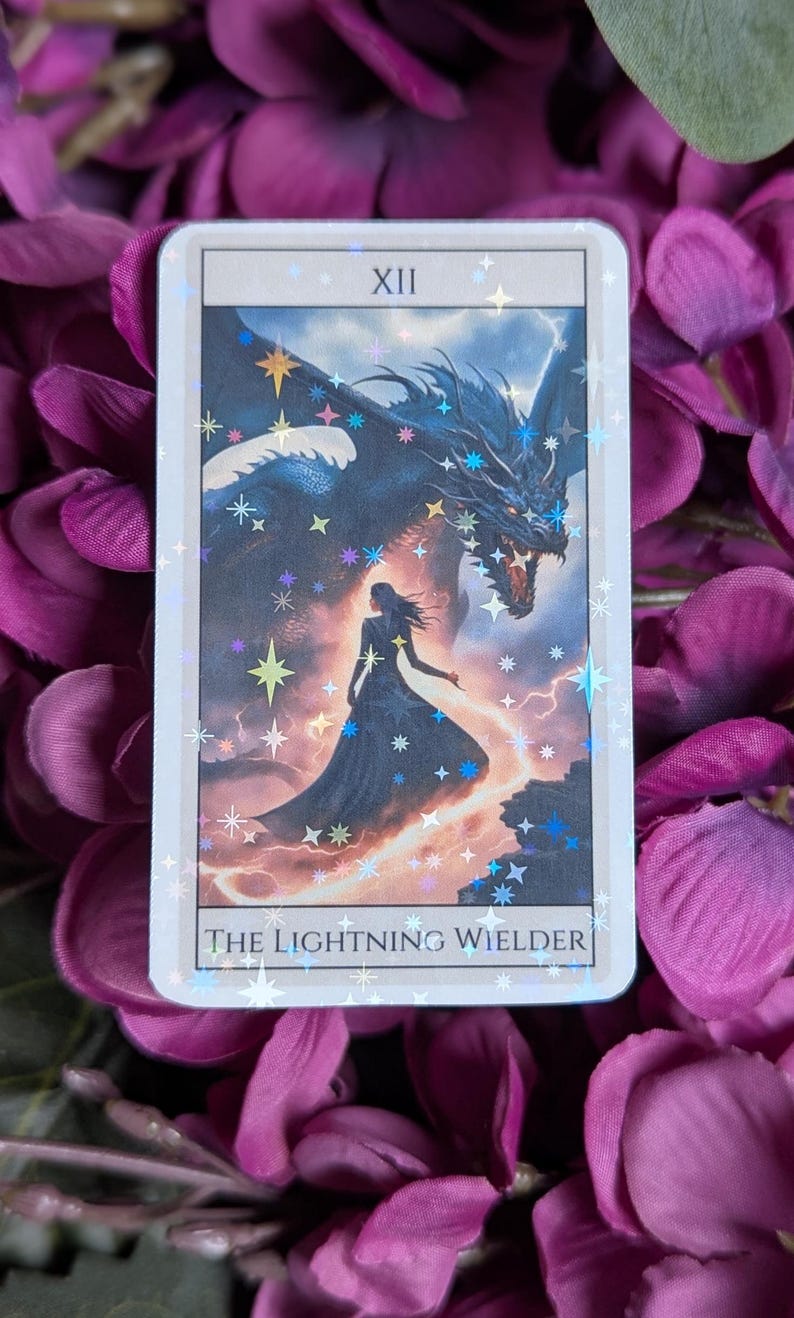 May include: A tarot card with a holographic finish depicting a woman standing in front of a blue dragon with lightning bolts. The card is labelled "XII THE LIGHTNING WIELDER".
