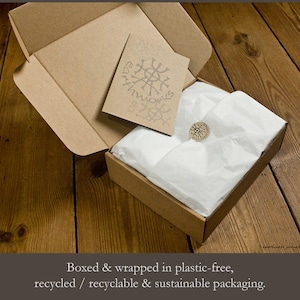 May include: A brown cardboard box with a white tissue paper lining. The box is closed and has a sticker on the top that says "Earthworks".