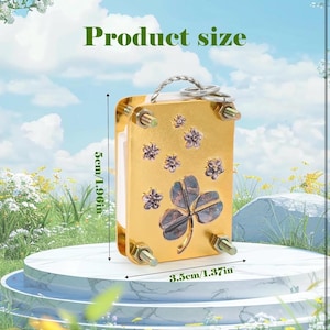 以下が含まれることがあります： 四つ葉のクローバーのデザインが施された金色の金属製のキーホルダー。キーホルダーの高さは5cm、幅は3.5cmです。