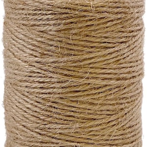 May include: A cylindrical spool of natural jute twine. The twine is tightly wound, creating a textured surface. A loop of twine extends from the top, suggesting it's ready for use in crafts, gardening, or packaging. The color is a warm, earthy brown.