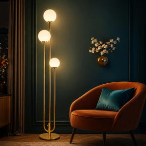 May include: A tall floor lamp with a gold-toned metal frame and three vertical stems of varying heights. Each stem is topped with a spherical white glass globe light. The lamp features a circular base and emits a warm, soft glow from the bulbs.