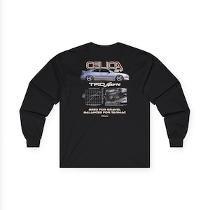 May include: Black long-sleeve shirt featuring a graphic of a silver Celica GT car with the text "CELICA GT" above it. Below the car is the text "TRD Sports" and "BRED FOR GRAVEL BALANCED FOR TARMAC".