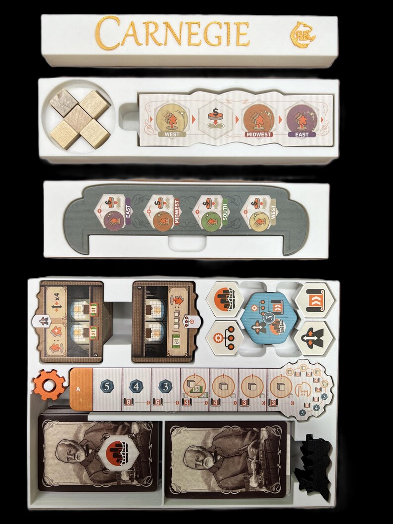 May include: A white organizer with the word "Carnegie" printed on the top. The organizer has multiple compartments for storing game pieces, cards, and other accessories. The organizer is designed for the board game "Carnegie".