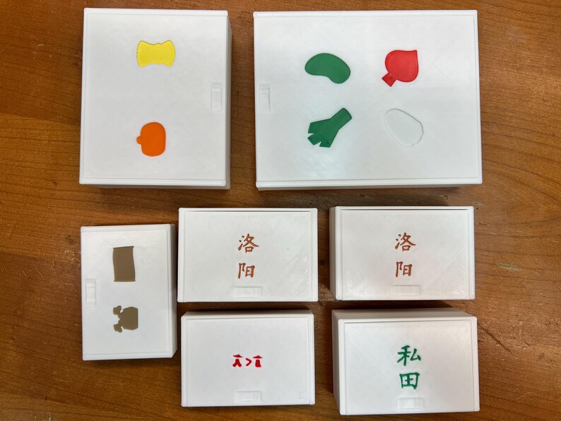 May include: Eight white square boxes with different colored shapes and Japanese characters. The shapes include a yellow bow tie, an orange pumpkin, a brown rectangle, a green bean, a green leaf, a red tomato, and a white circle. The Japanese characters are "發問" and "本田".