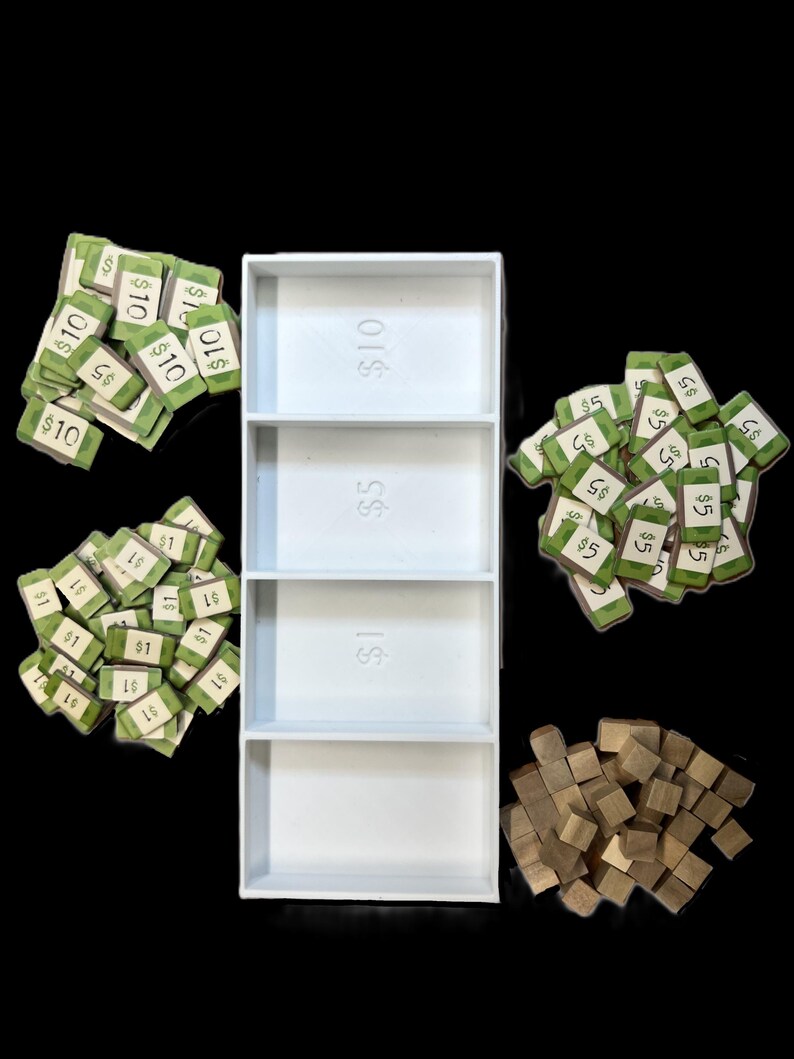 May include: A white plastic tray with three compartments, each labeled with a dollar amount: $1, $5, and $10. The tray is filled with stacks of green paper money, with denominations of $1, $5, and $10. There are also a pile of small wooden blocks.