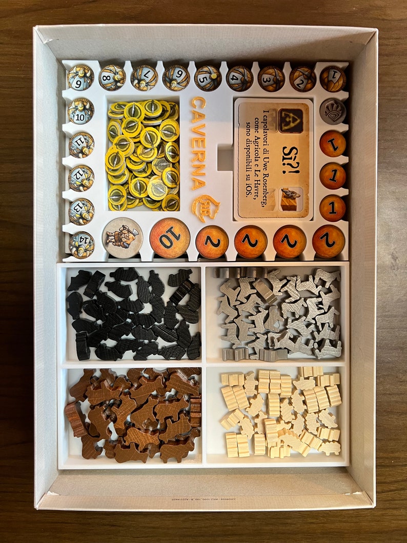 May include: A white foam insert with compartments for storing game pieces for the board game Caverna: The Cave Farmers. The insert includes compartments for wooden meeples, wooden cubes, and plastic tokens. The insert also includes a card holder for the game's rulebook.