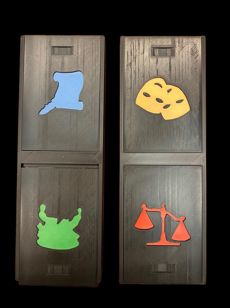 May include: Two wooden boxes with different colored shapes cut out. The top box on the left has a light blue hat shape, the bottom box has a green monster shape. The top box on the right has a yellow mask shape, the bottom box has a red scale shape.