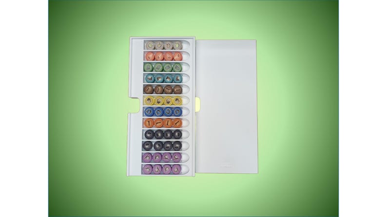 May include: A white plastic storage case with a clear lid containing a collection of colorful round beads. The beads are arranged in rows and are different colors, including red, orange, yellow, green, blue, purple, and black.