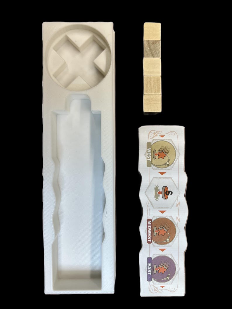 May include: A white foam insert with a cross-shaped cutout and a long rectangular slot. There are four wooden blocks stacked on top of each other. A white card with the words "East", "Midwest", and "West" and illustrations of a maple leaf, a spinning top, and a beehive.
