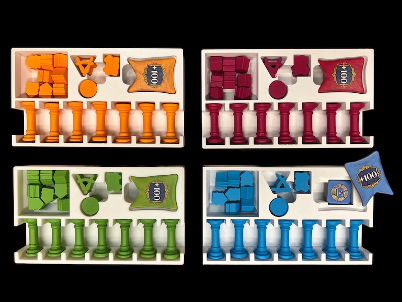 May include: Four white trays with different colored game pieces and cards. Each tray has 10 columns with small pillars in each column. The trays have a card with the text " +100" in the top right corner. The colors of the game pieces are orange, red, green, and blue.
