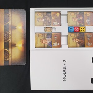 May include: A board game set with cards, dice, and a game board. The cards feature illustrations of people and symbols. The dice are blue, red, and yellow. The game board has a brown and gold design with a maze-like pattern.