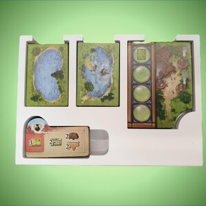 May include: White foam insert with four slots for game cards. The insert has a slot for a small card with the numbers 2 and 3 on it. The cards have green, blue, and brown backgrounds with illustrations.