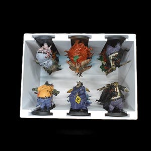 May include: A set of six detailed, colorful figurines of grotesque characters, each with unique designs and poses. The figures are arranged in a white display box against a black background, showcasing their intricate features and vibrant colors.