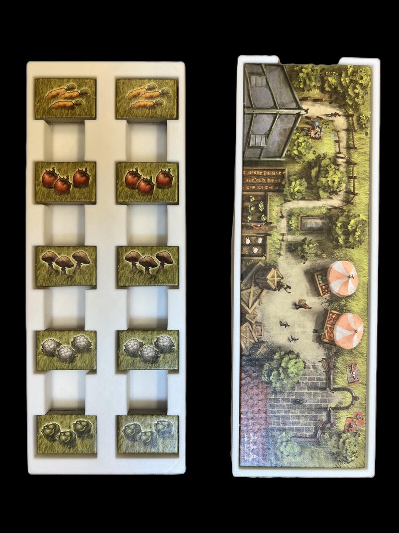 May include: A white foam insert with 10 compartments for storing game pieces. The compartments are filled with small, colorful game pieces depicting various vegetables. A separate white foam insert with a printed image of a village scene.