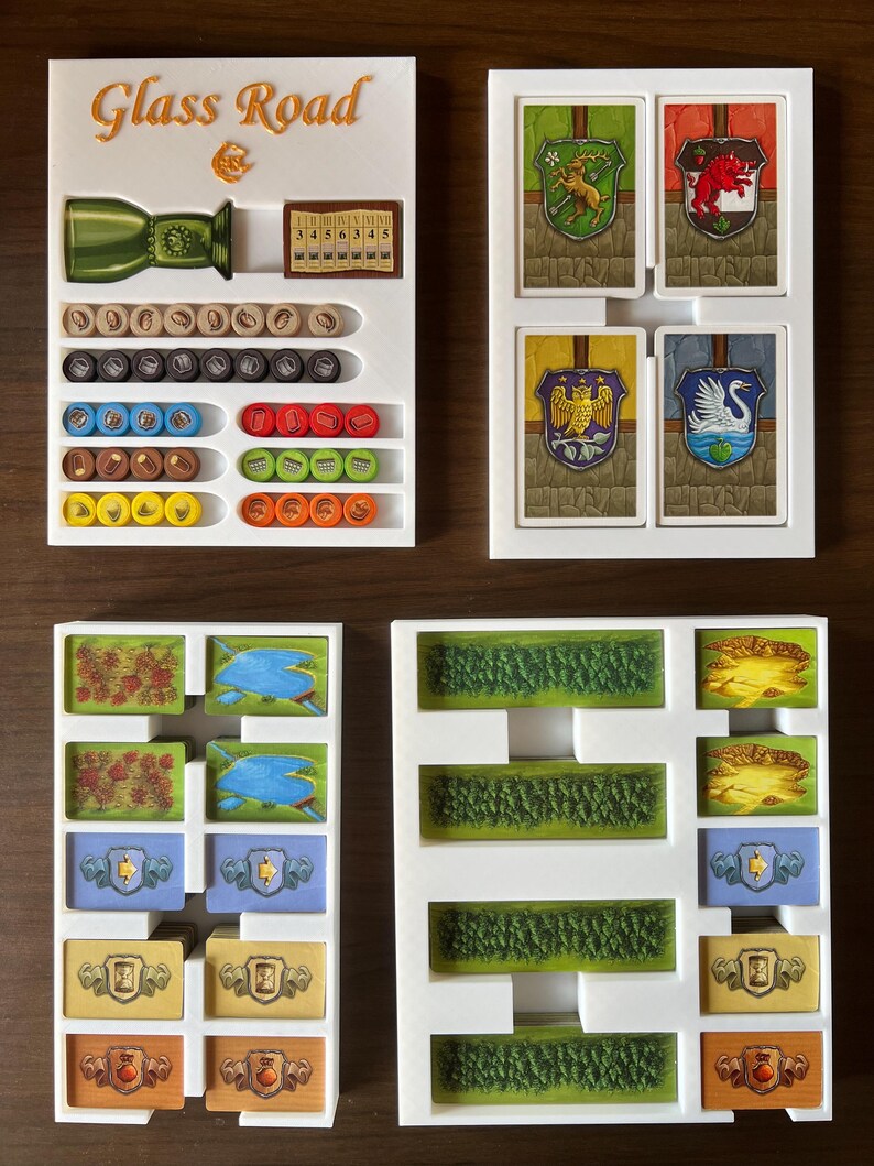 May include: White plastic organizer with compartments for storing game pieces and cards. The organizer has the words "Glass Road" printed on the top. The organizer has compartments for storing different colored tokens, dice, and cards.