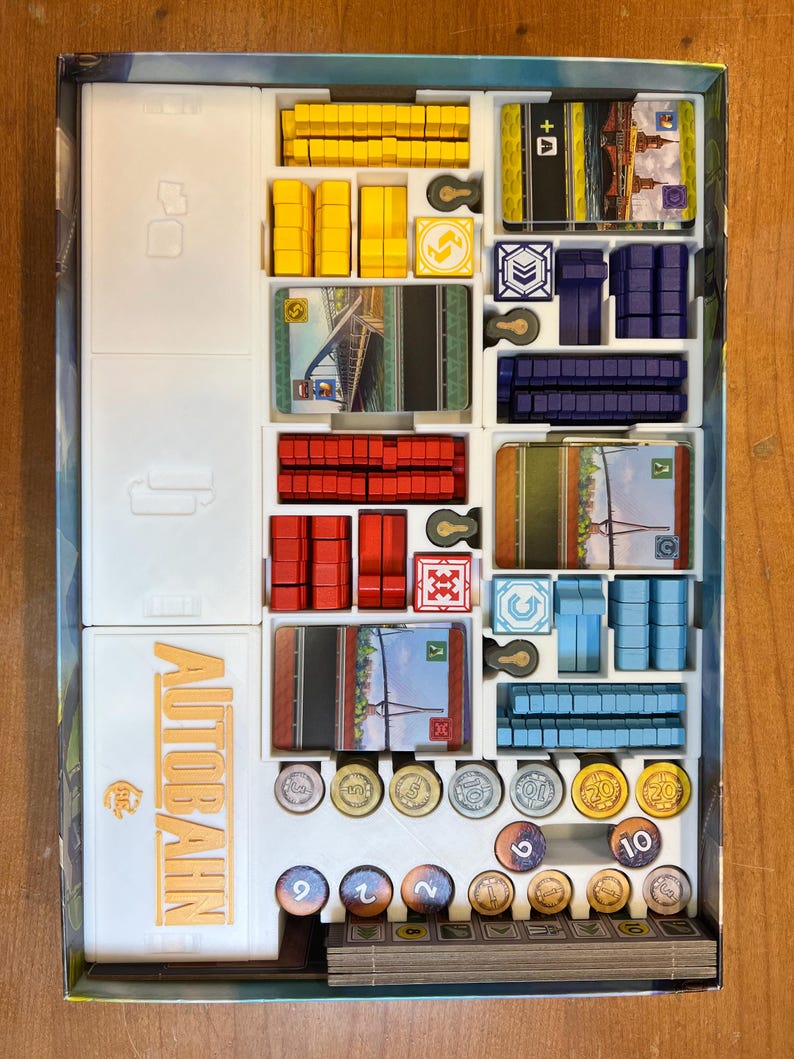 K&ouml;nnte beinhalten: Ein wei&szlig;er Organizer-Einsatz f&uuml;r das Brettspiel "Autobahn" mit F&auml;chern f&uuml;r Spielfiguren, Karten und Spielmarken. Der Einsatz tr&auml;gt ein Etikett mit der Aufschrift "Autobahn".