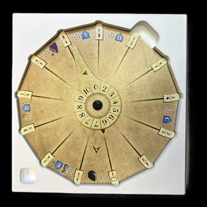 May include: A circular game board with a rotating dial in the center. The dial has numbers 0 through 9. The board has 12 sections with numbers 1 through 3 and symbols. The board is beige with brown accents.