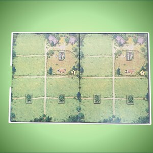 May include: A game board with two identical sides, each featuring a green field with a small village, a barn, and a field with a number "2" on it. The board is divided into squares with paths.
