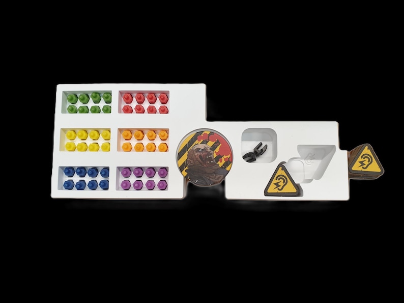 May include: A white game organizer with compartments holding colorful game pieces. Includes green, red, yellow, orange, blue, and purple pieces. Also features game tokens and a circular game piece with a graphic.