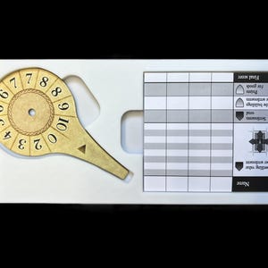 May include: A white plastic game board with a gold and black numbered dial, a gridded score sheet, and a section for final score. The score sheet has headings for dwelling value, settlements, total, points for the buildings and the settlements, and points for goods.