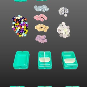 以下が含まれることがあります： 透明な蓋が付いたティールプラスチック容器、さまざまな色のゲームピース、白いゲームディバイダーなど、ボードゲームコンポーネントのコレクション。ピースには、カラフルなビーズ、ピンクと黄色のリング状のトークン、銀色のコインのようなトークンが含まれます。