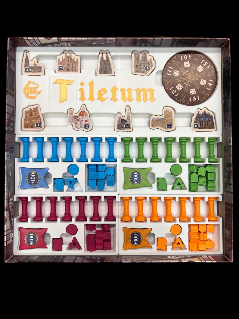 May include: A game box with the title "Tiletum" printed on the lid. The box contains various game pieces, including wooden tiles, plastic columns, and plastic cubes in blue, green, red, and orange.