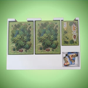 May include: White plastic organizer with three compartments for storing game pieces. The compartments contain green and brown illustrated cards and small blue and white game pieces.