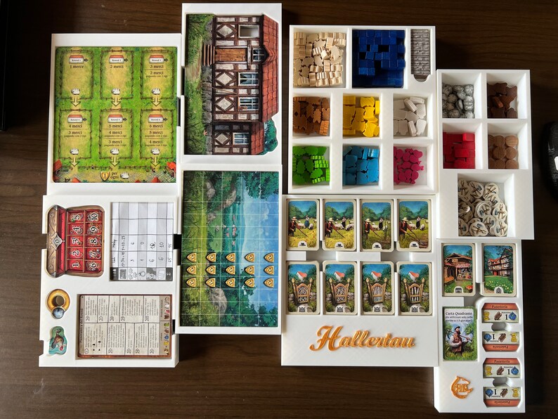May include: White organizer with compartments for storing game pieces and cards. The organizer has a label that says "Hallertau".