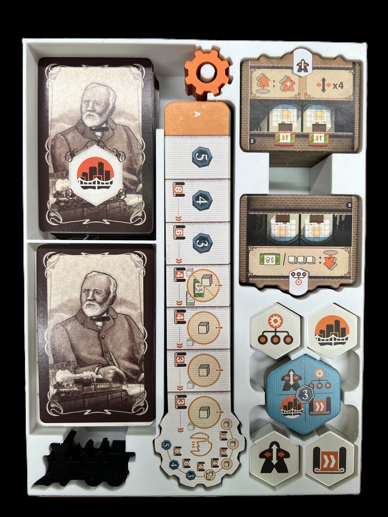 May include: A white organizer tray with compartments for storing a board game. The tray contains cards, tokens, and a gear-shaped piece. The cards feature illustrations of a man in a suit and a cityscape. The tokens are in various colors and shapes, including a blue hexagon with a cityscape and a gear.