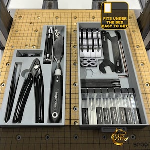 May include: A gray plastic storage box with two drawers, one containing a variety of tools, including pliers, screwdrivers, and wrenches, and the other containing a set of small tools. The box has a label that reads "Fits under the bed, easy to get".