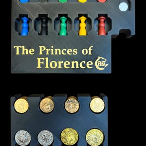 K&ouml;nnte beinhalten: Ein schwarzer Plastik-Spielorganizer mit dem Titel "The Princes of Florence" in goldenen Buchstaben. Der Organizer hat F&auml;cher f&uuml;r Spielfiguren und M&uuml;nzen. Die Spielfiguren sind in den Farben Blau, Schwarz, Gr&uuml;n, Gelb und Rot. Die M&uuml;nzen sind aus Gold und Silber.