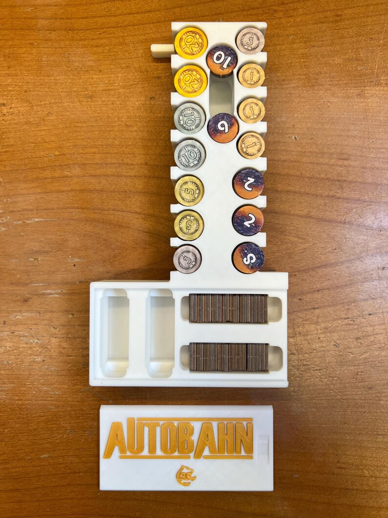 Pode incluir: Organizador de pl&aacute;stico branco para o jogo de tabuleiro Autobahn. Tem ranhuras para diferentes pe&ccedil;as de jogo coloridas e um compartimento para pe&ccedil;as de madeira. A tampa tem o logotipo do jogo, "AUTOBAHN", em letras douradas.